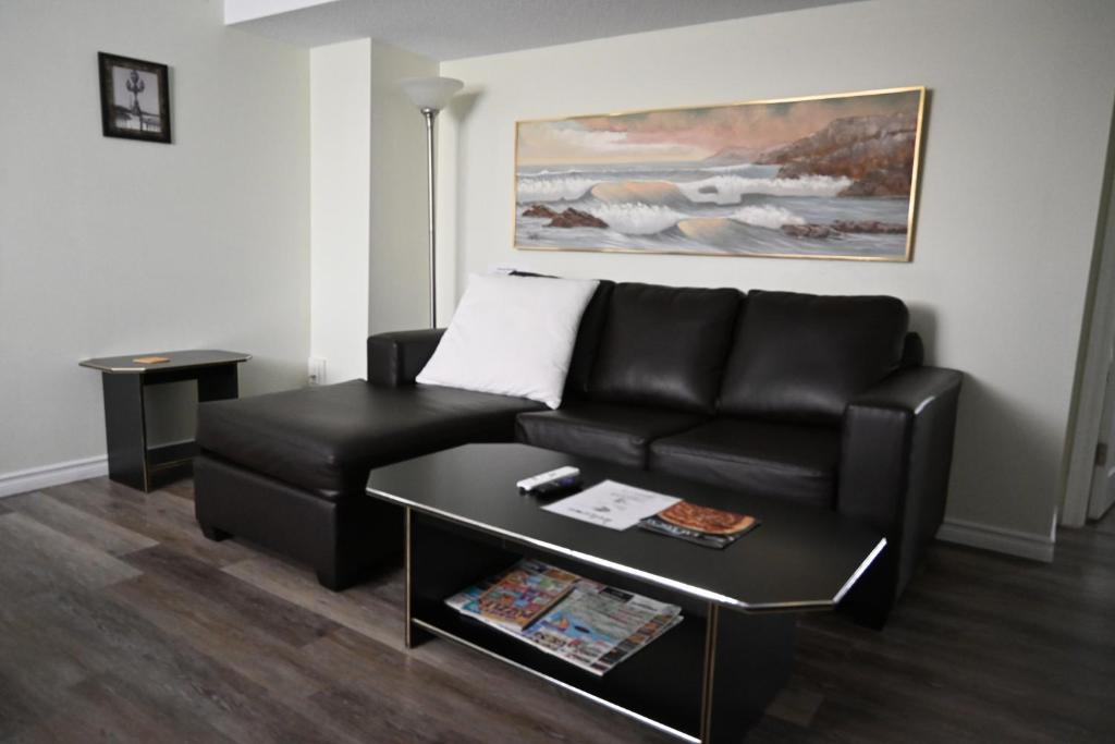 a living room with a black leather couch and a table at Metropolitan Suite in Niagara Falls