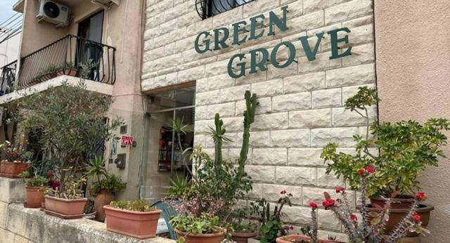 a green groove sign on the side of a building with plants at Green Grove Guest House in St. Julianʼs