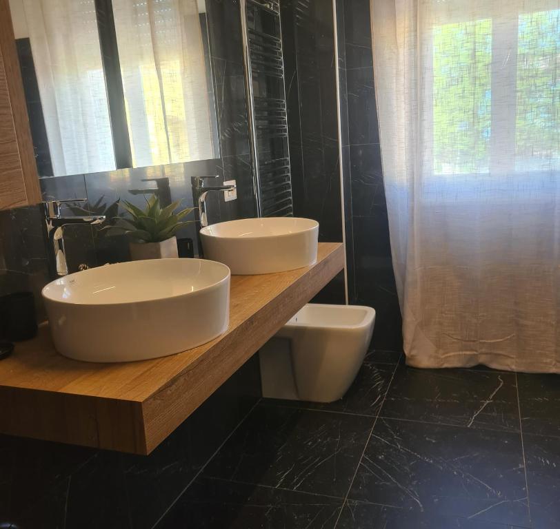 2 lavandini su un bancone in legno in bagno di Cascina Antiche Terre a Campegine