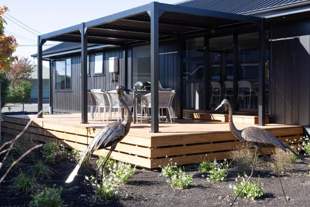 dos pájaros parados en una terraza de madera al lado de una casa en The Corner on Te Mata, en Havelock North