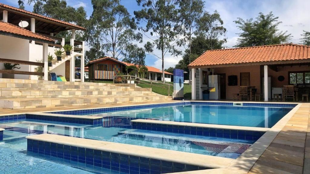 ein Pool mit Treppe und ein Haus in der Unterkunft Sítio São Luiz, R1: Desfrute da Natureza e Relaxe in Quadra