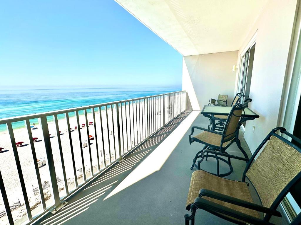 Un balcón con sillas, una mesa y el océano en Windemere Unit 605, en Pensacola