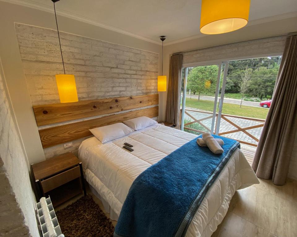 um quarto com uma cama e uma grande janela em Pousada Viviê CENTRAL em Monte Verde