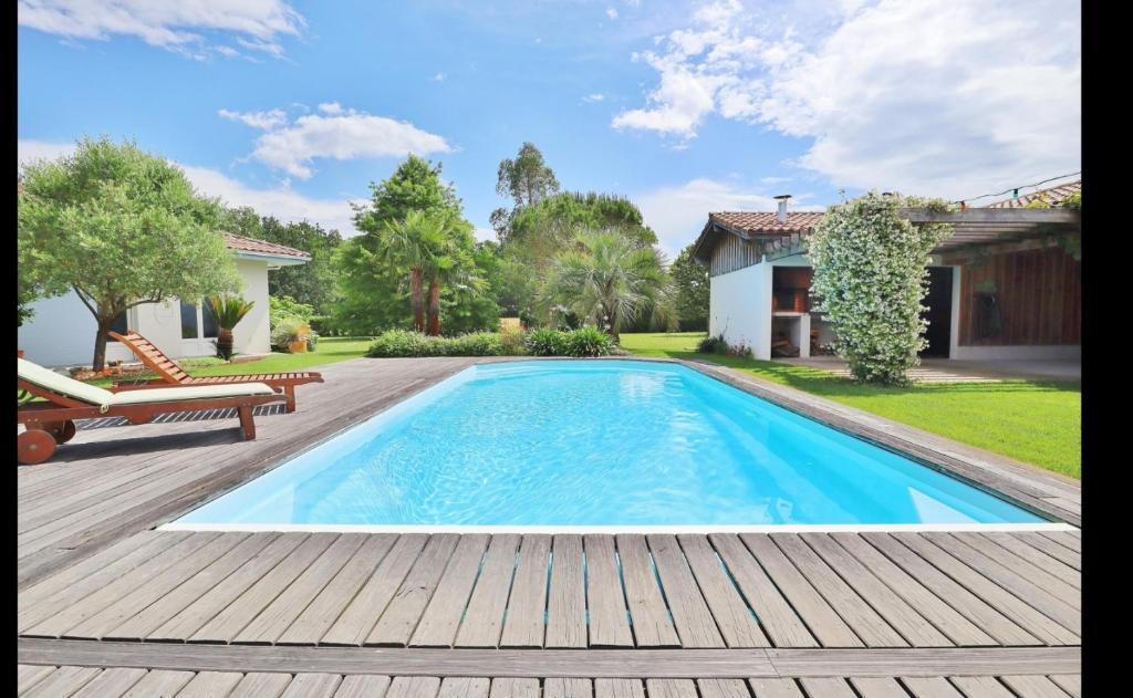 une piscine avec une terrasse en bois et une maison dans l'établissement Le spot Landais - Le gîte, à Soustons