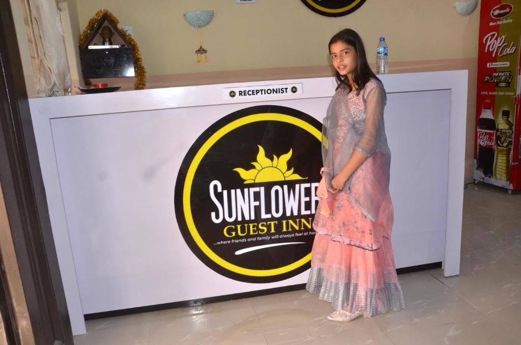 a woman in a dress standing in front of a sign at Sunflower Guest inn in Kano