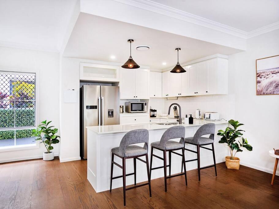een keuken met witte kasten en een aanrecht met stoelen bij Broadwater Lux home in Gold Coast
