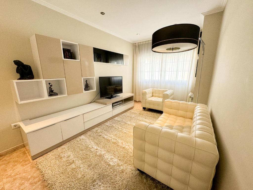ein Wohnzimmer mit einem weißen Sofa und einem TV in der Unterkunft Casa Baltar, Sanxenxo, a 100m de la playa de Baltar in Sanxenxo