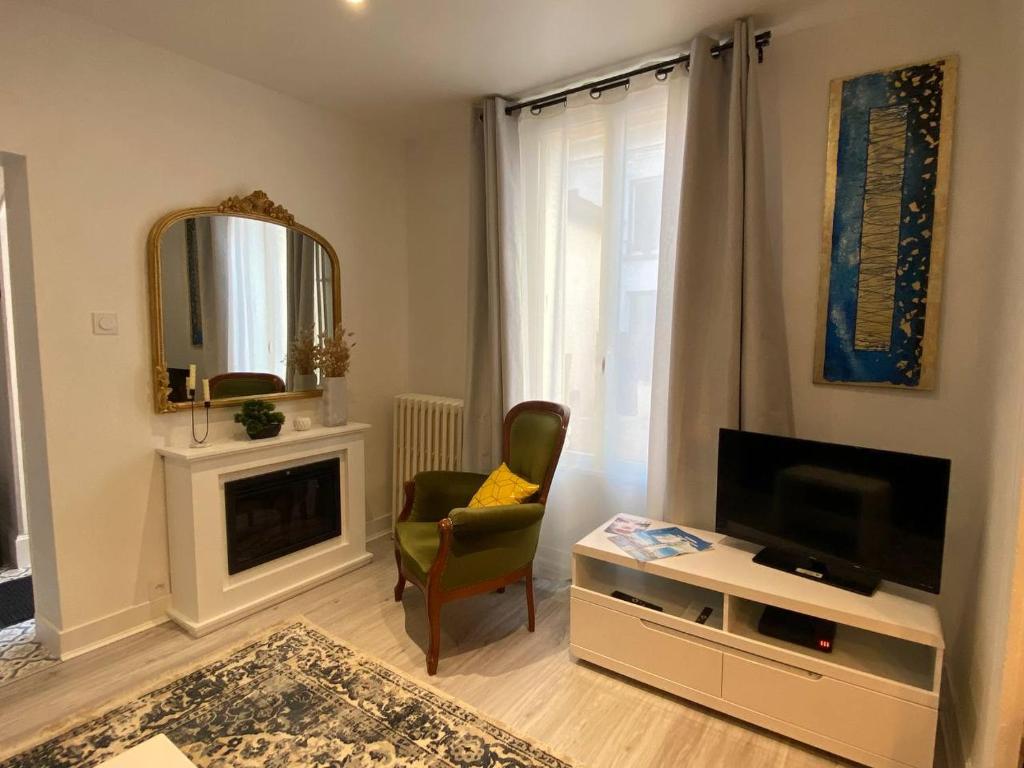 Una sala de estar con un televisor y una silla. en Maison Cosy à Vichy, en Vichy
