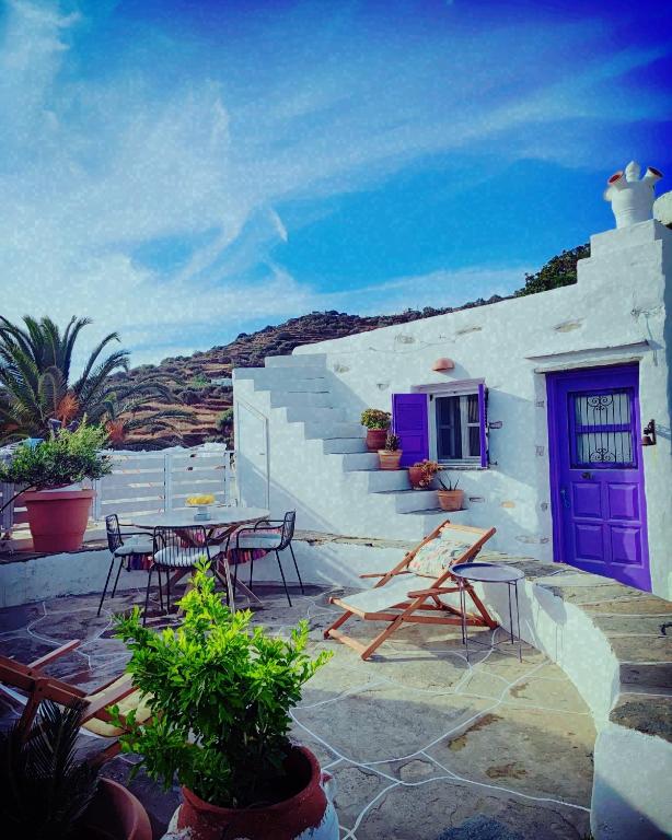 - un bâtiment blanc avec une porte violette, une table et des chaises dans l'établissement Sifnos Twin Houses, à Apollonia