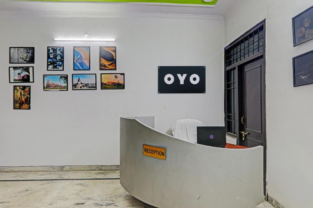 een witte kamer met een bureau met een bord aan de muur bij OYO Flagship Drip Stay Inn in Lucknow