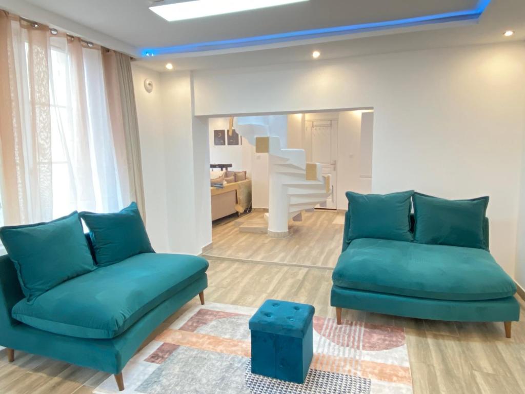 una sala de estar con sofás azules y una escalera. en Chambre spacieuse élégante en Beauvais