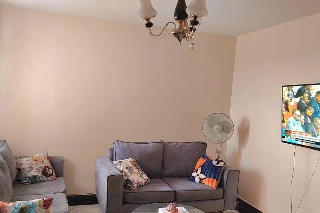 a living room with a couch and a fan at Ecohome 5 wilderness within sight of the Airport in Nairobi