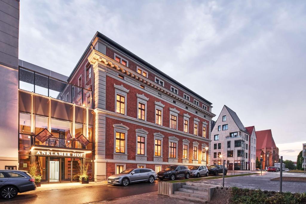 un grand bâtiment en briques avec des voitures garées devant lui dans l'établissement Hotel Anklamer Hof, BW Signature Collection, à Anklam