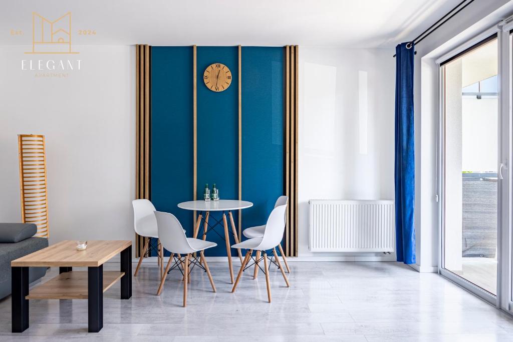 a dining room with a table and chairs and a clock on a wall at ELEGANT Apartment Mechaniczna 5W in Głogów