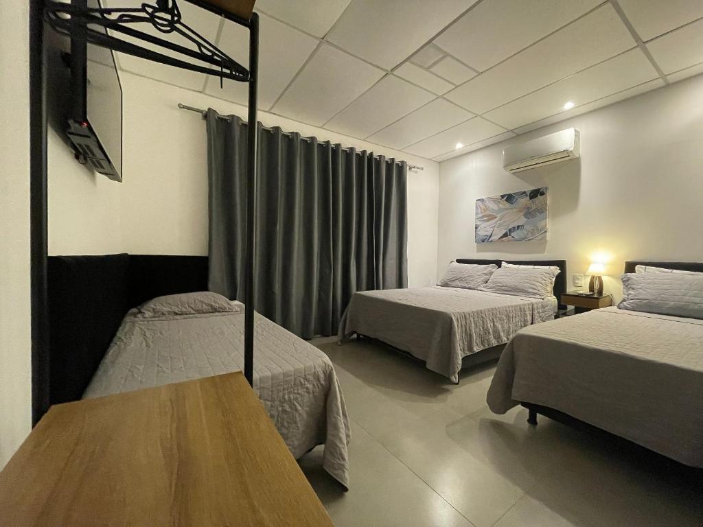 um quarto de hotel com duas camas e uma mesa em VILLA BILAC 08 - Aconchegante Studio próximo à Vila Germânica em Blumenau
