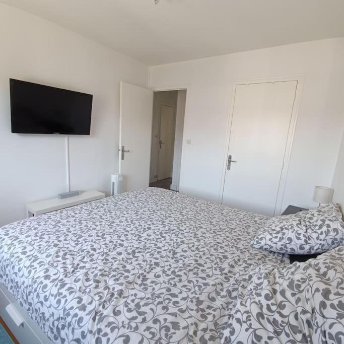 une chambre avec un lit et une télévision au mur dans l'établissement Magnifique T3 - Calme & tout équipé - Avec Vue & Parking Privé Gratuit, à Grenoble