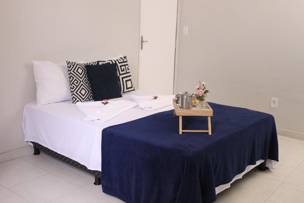 Bett in einem Zimmer mit einem Tisch und einer blauen Decke in der Unterkunft Pousada Casa Mar Pajuçara in Maceió