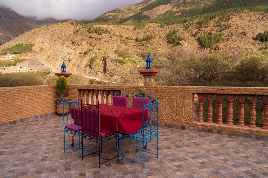 une table et des chaises sur une terrasse avec une montagne dans l'établissement Riad Tourtit, à Imlil