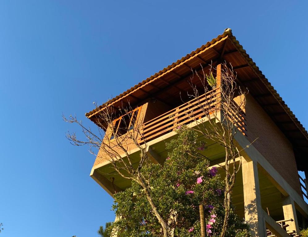 - un bâtiment avec un balcon sur le côté dans l'établissement Pousada Chales Joao de Barro, à Visconde de Mauá