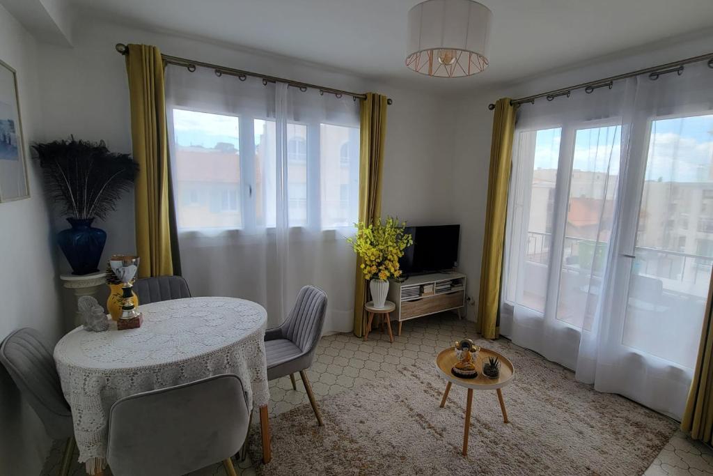 un salon avec une table, des chaises et des fenêtres dans l'établissement Apartment in the heart of Saint-Raphaël, à Saint-Raphaël
