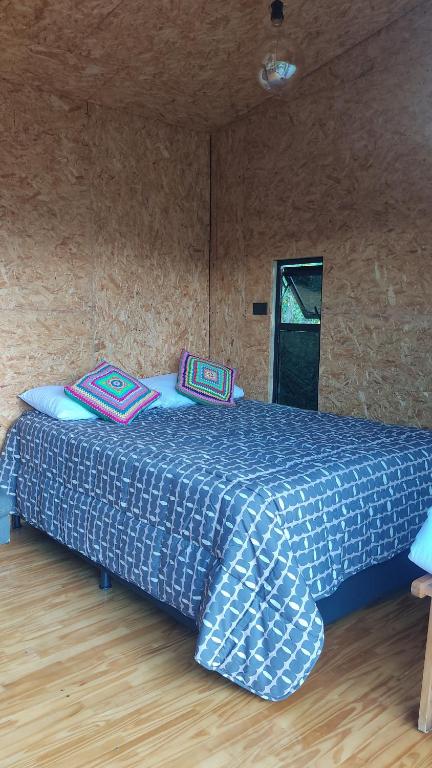 een slaapkamer met een blauw bed met kussens erop bij cabaña madera in Guarne
