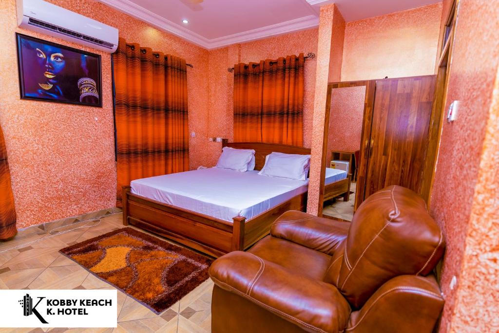 sypialnia z łóżkiem i skórzanym krzesłem w obiekcie Kobby Keach K Hotel w mieście Kumasi