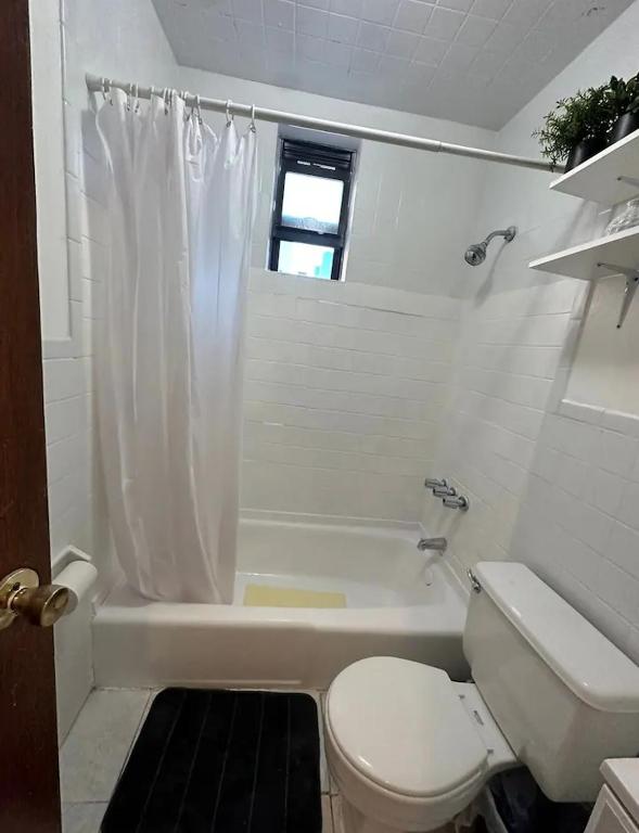 een witte badkamer met een toilet en een bad bij The 30 Day Stay Vibrant House in New York