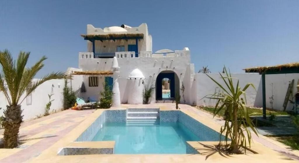 a house with a swimming pool in front of it at Djerba Advent in Bou Menjel