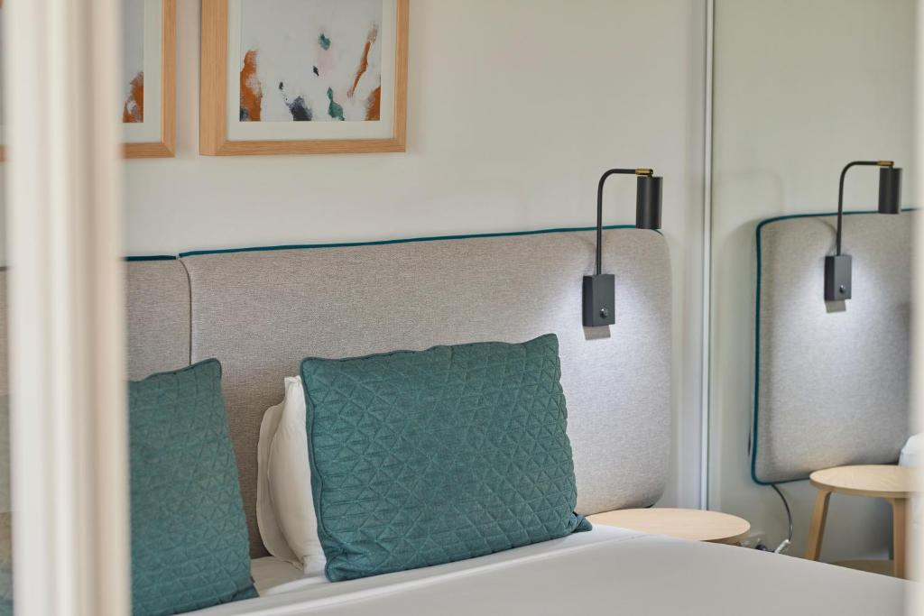 a bedroom with a bed with two green pillows at Quest Cannon Hill in Brisbane
