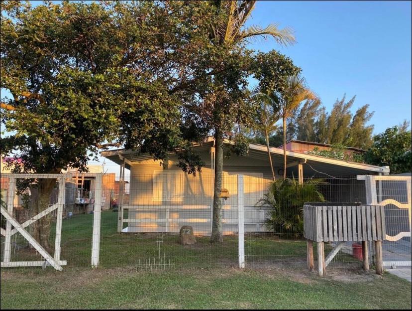 ein Haus mit einem Zaun und einer Bank davor in der Unterkunft Casa de férias! in Capão da Canoa