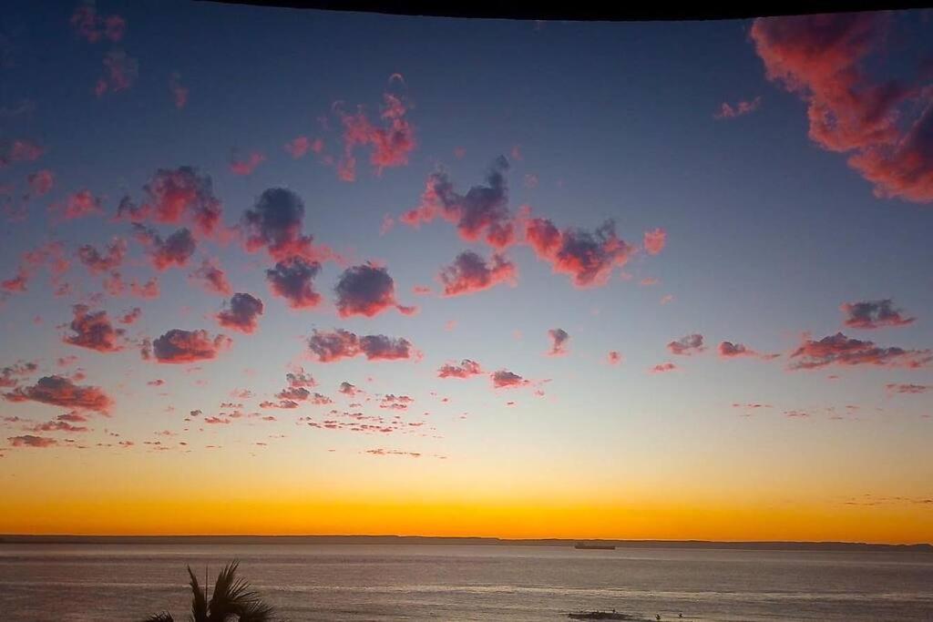 Una puesta de sol en una playa con un cielo azul y naranja. en Condominio Estilo Mexicano en la playa, en La Paz