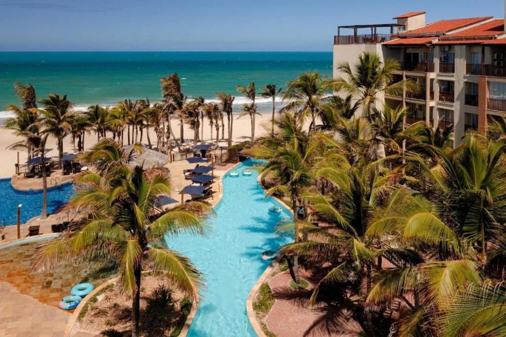 uma vista aérea de um resort com palmeiras e da praia em Belíssimo Apartamento no resort do Beach Park - By Ideal Trip Hospedagens em Aquiraz