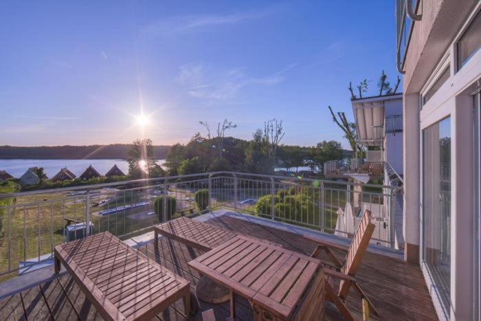 a deck with a wooden table and chairs on a balcony at Strandläufer Classic 211 in Granzow