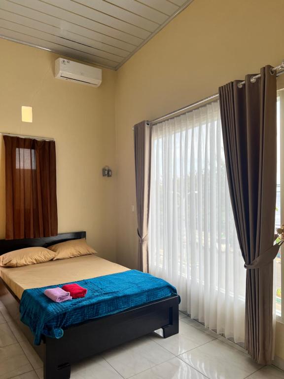 a bedroom with a bed and a large window at KBI Hostel in Ternate