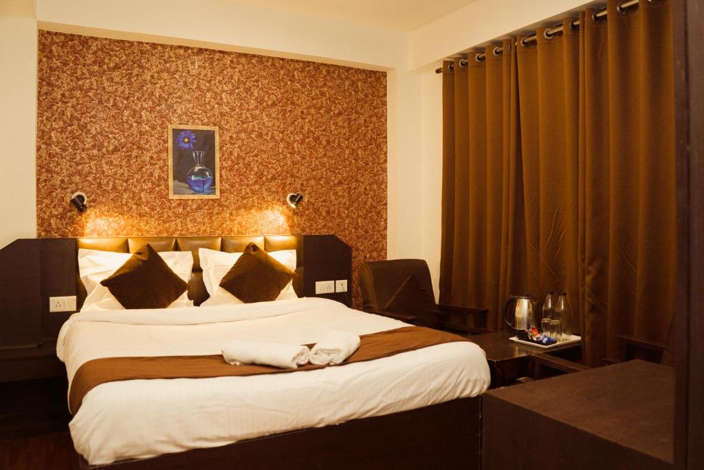 a hotel room with a large bed with white sheets at Hotel Siddhi Vinayak Regency,near Mg Marg, Gangtok in Gangtok