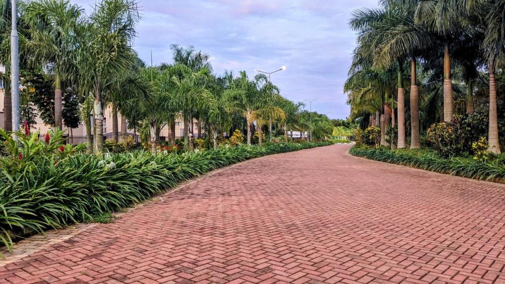 a brick road lined with palm trees and plants at Bella Vista in Wakiso