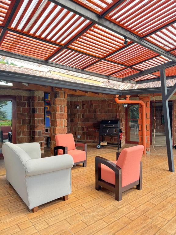 a covered patio with chairs and a fireplace at FINCA VILLA LORA GIRARDOTA in Girardota