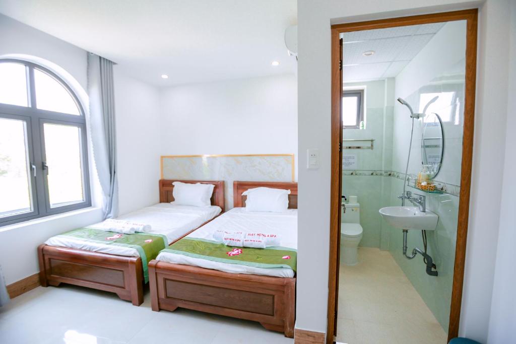 ALEX HOTEL AND SPA في An Bàn: غرفة نوم بسرير ودش ومغسلة
