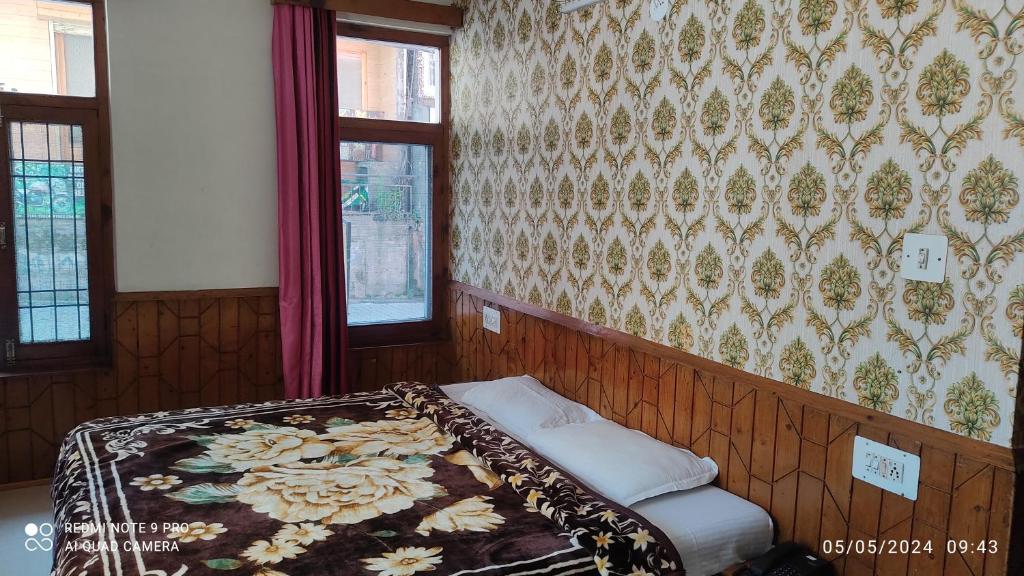 HOTEL UNIQUE في مانالي: سرير في غرفة مع جدار