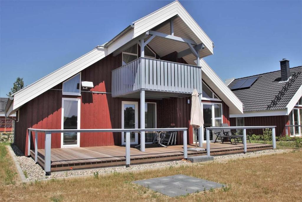a red house with a deck and a table at Seeschwalbe Classic 310 in Mirow