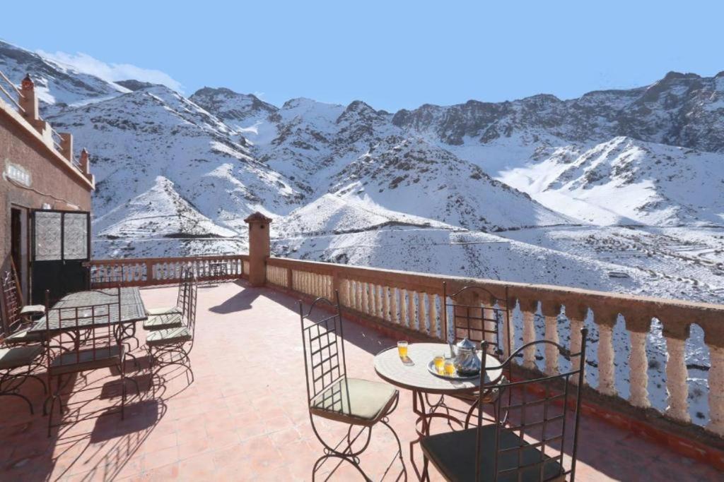 una mesa y sillas en un balcón con montañas cubiertas de nieve en Locanda Lodge, Marrakech Tacheddirt en Marrakech