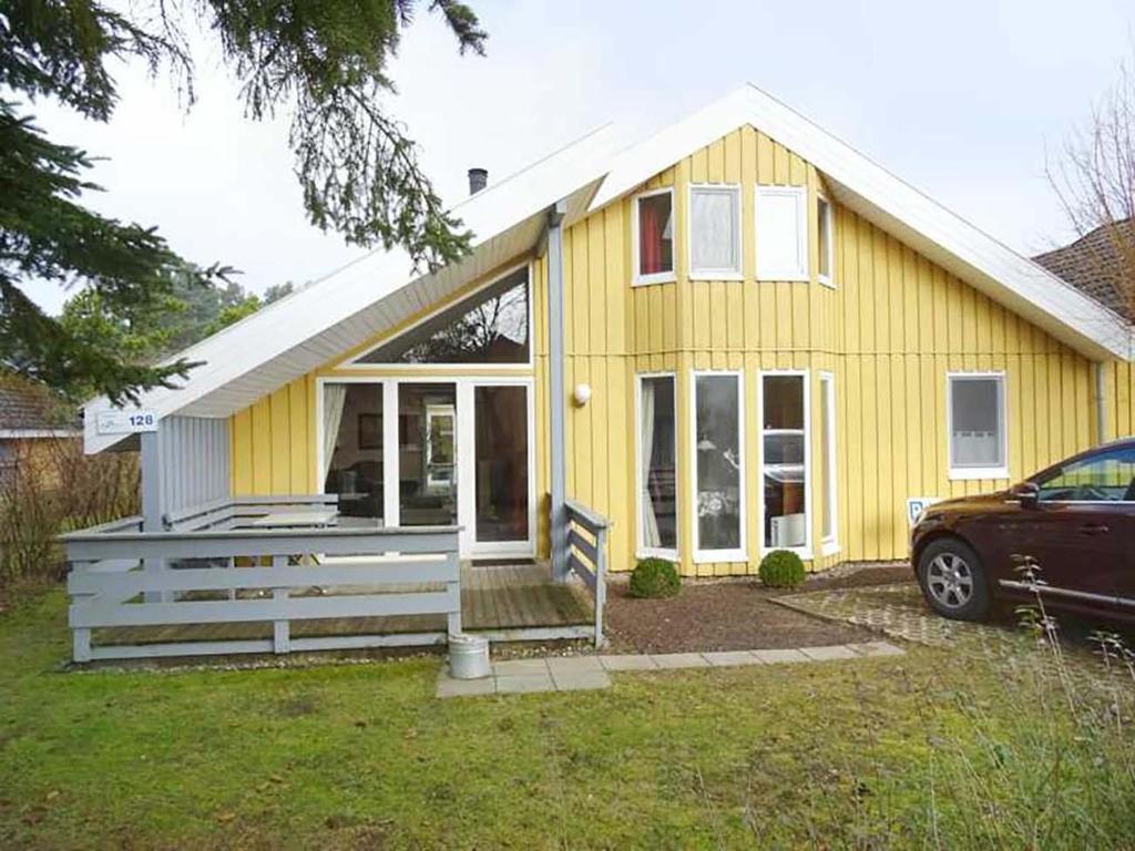 a yellow house with a car parked in front of it at Wildgans 128 in Mirow