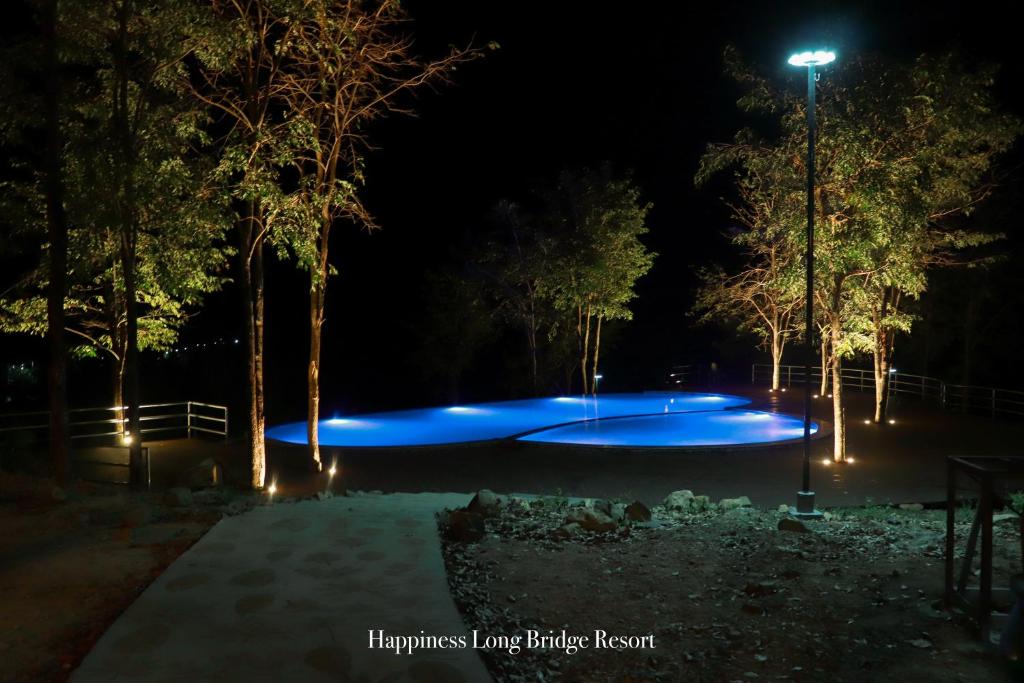 uma piscina à noite com luzes azuis em Happiness Long Bridge Resort 
