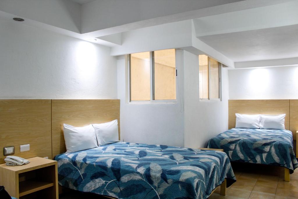 a hotel room with two beds and two windows at Hotel Nueva Zelanda in León
