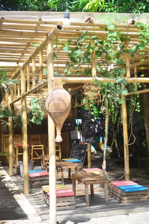 eine hölzerne Pergola mit Bänken und Tischen und einer Vase in der Unterkunft Mango Tree House in Gili Trawangan