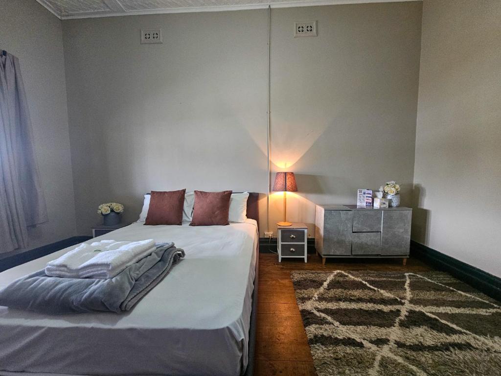 1 dormitorio con 1 cama y 1 mesa con lámpara en Bellbird Hotel en Cessnock