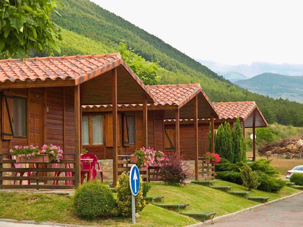 a small wooden house with a mountain in the background at Camping Valle de Tena in Sabiñánigo