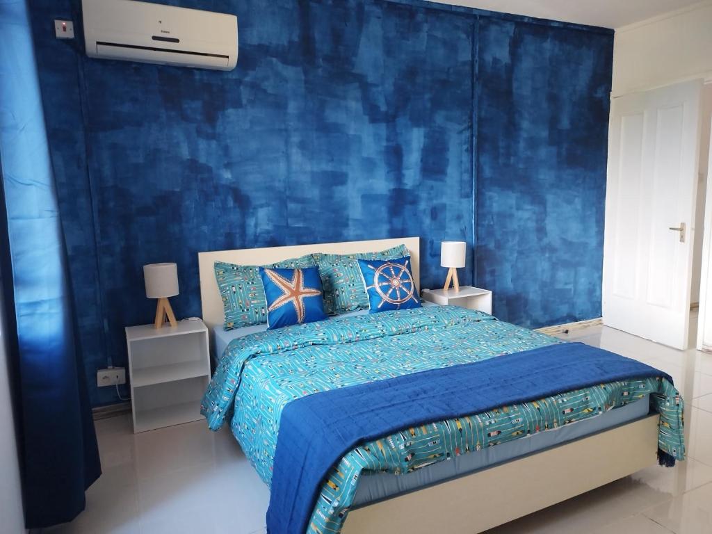 een blauwe slaapkamer met een bed met blauwe muren bij Morsky Vanek Apartment in Flic-en-Flac