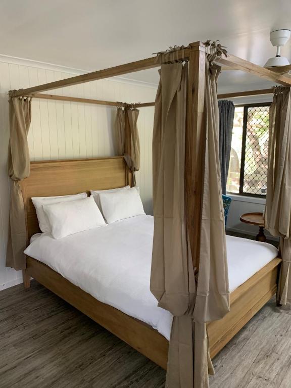a bedroom with a canopy bed with white pillows at Turtle Cove Lake Front Cabin 300m To Beach in Hervey Bay