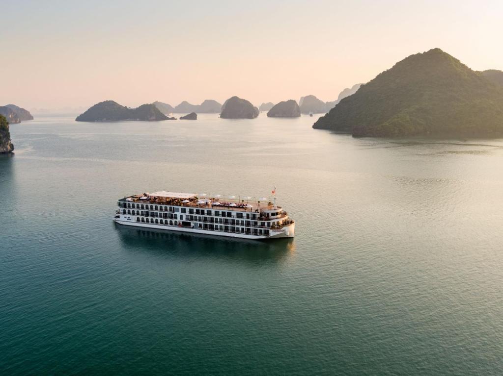 a cruise ship in the water with mountains in the background at Indochine Cruise Lan Ha Bay Powered by ASTON in Ha Long